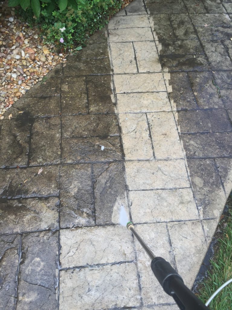 Person power washing the dirt half of a sidewalk making it clean and fresh looking new